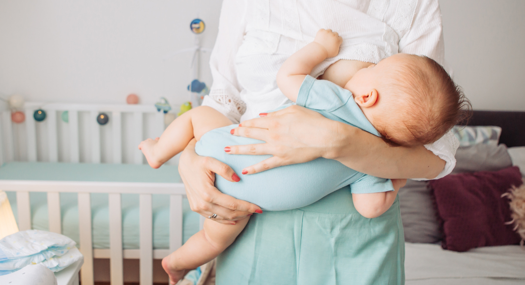 A woman breastfeeding a baby while standing. 