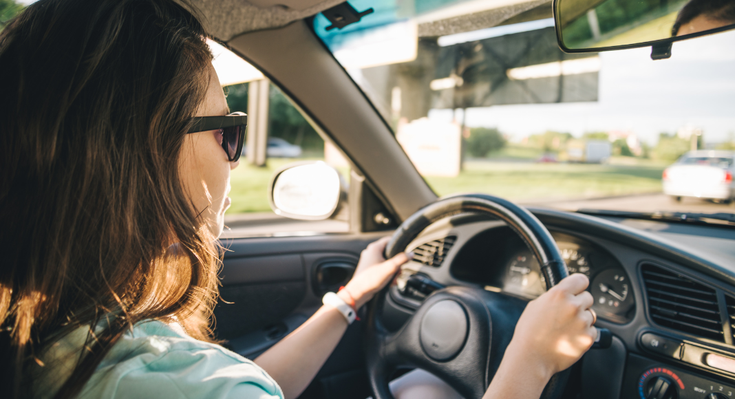 A woman behind the steering wheel of a car. 