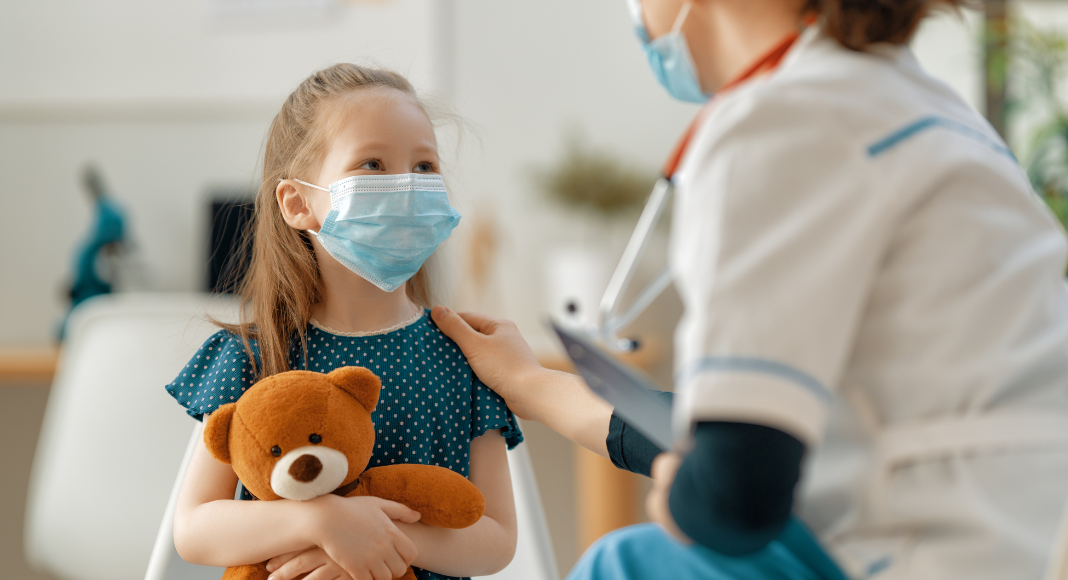 A girl holding a teddy bear being prepared for surgery.