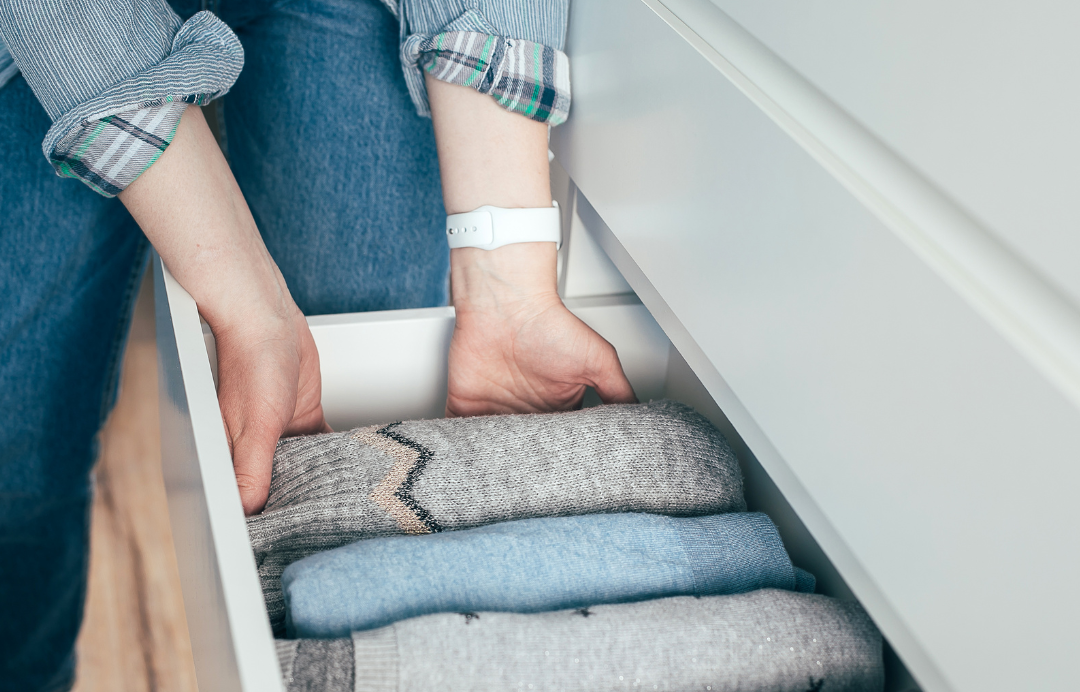 Organizing sweaters in a drawer.