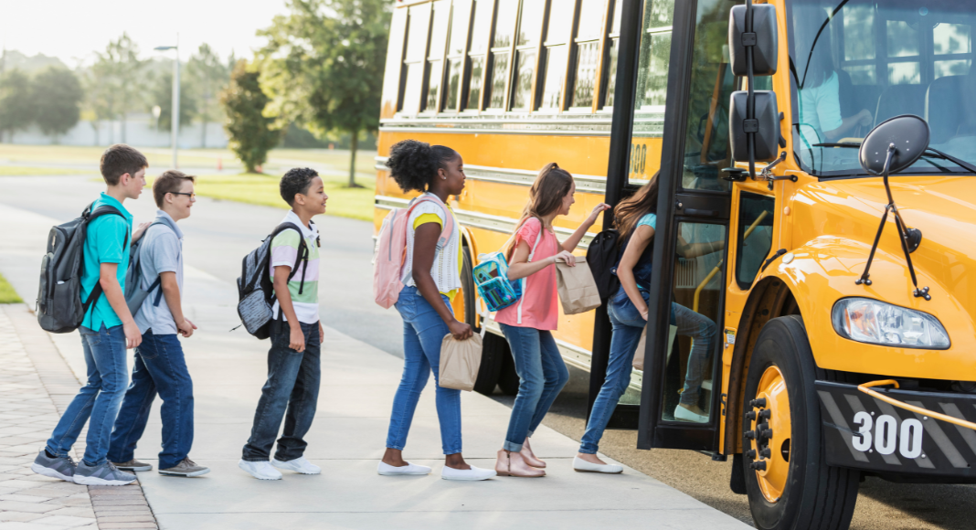 Children lined up to get on a school bus.