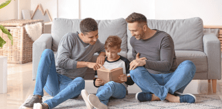 Best Books for Kids About Taking Pride in Yourself & Your Family Two dads reading to their son.