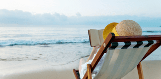 Summer Reading List: This One is for the Moms A woman reading a book on the beach.