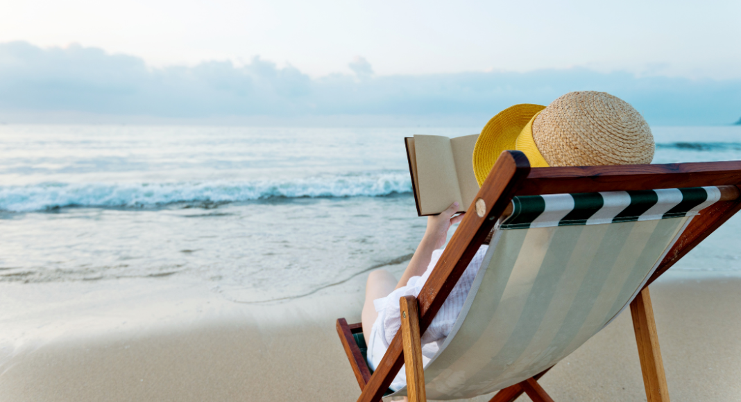 A woman reading a book on the beach.