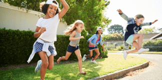 Kids playing outside and jumping off a curb.