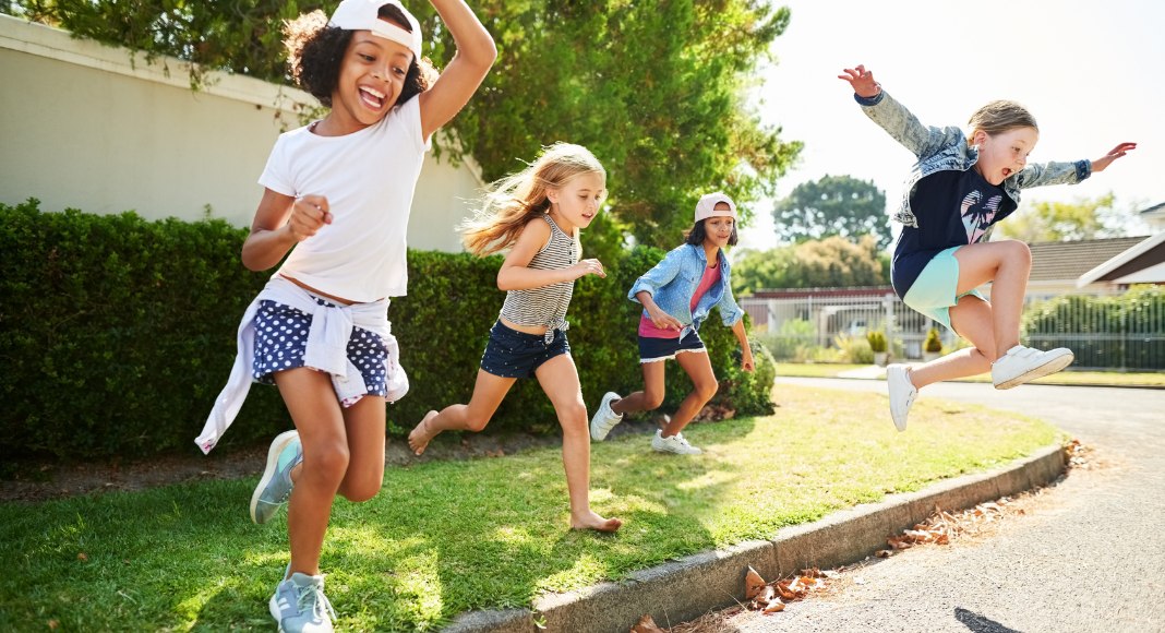 Kids playing outside and jumping off a curb.