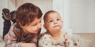 A toddler and baby laying on their bellies.