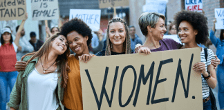 Women holding a sign that says "Women"