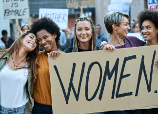 Women holding a sign that says "Women"