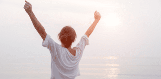 Be Limitless A woman raising her hands in the air in happiness.