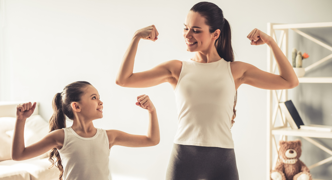 A mom and daughter making muscles.