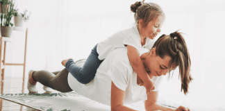 Forget the Scale: The Real Reasons Moms Need to Workout A mom exercising with her daughter on her back.