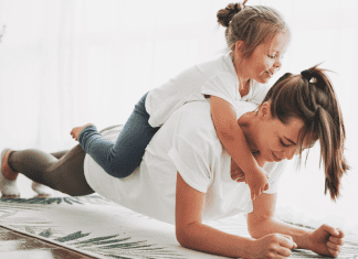 Forget the Scale: The Real Reasons Moms Need to Workout A mom exercising with her daughter on her back.