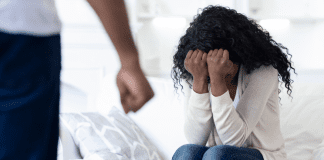 October is Domestic Violence Awareness Month A woman covering her face while a man stands in front of her with a clenched fist.