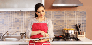 A woman looking through a cook book in the kitchen.