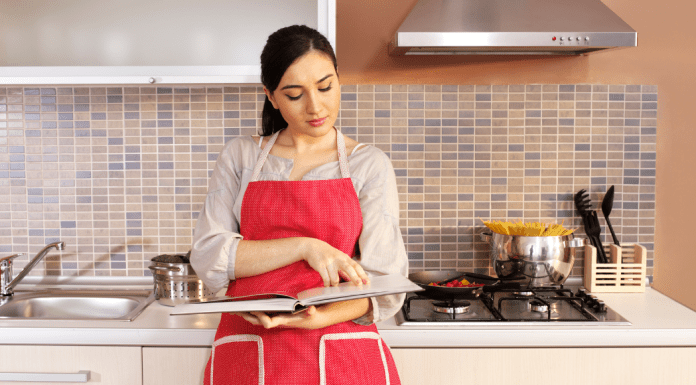 A woman looking through a cook book in the kitchen.