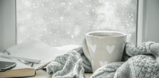 Essential Tips to Prepare Your Home for Winter A mug of coffee wrapped in a scarf by a winter window.
