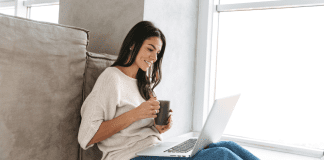 A woman drinking coffee while reading on her computer.