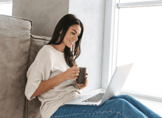 A woman drinking coffee while reading on her computer.