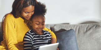 A mother looking at a tablet with her daughter.