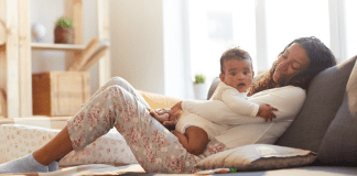 How to Prioritize Your Wellness in the New Year as a Mom A mother laying on the couch holding her baby.