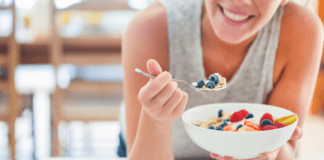 Healthy Eating Tips for the New Year A woman eating a bowl of cereal with fruit.