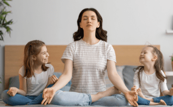 A mom meditating with her daughters.