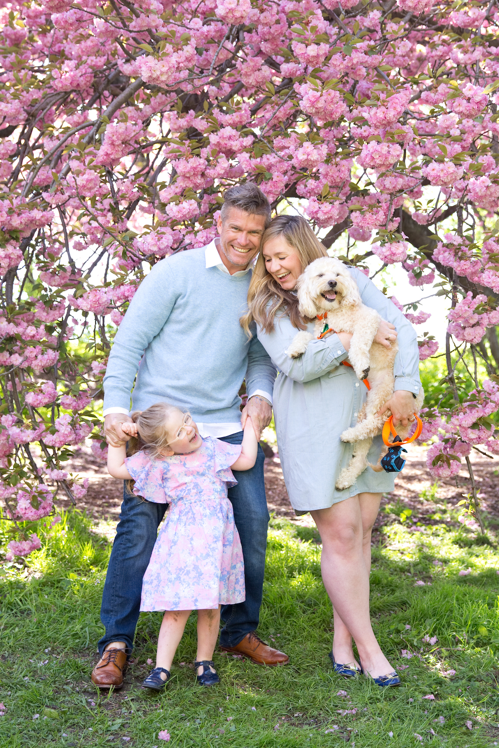 A family photographed under a tree of flowers.
