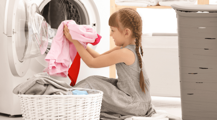 A young girl putting clothes in a washing machine.