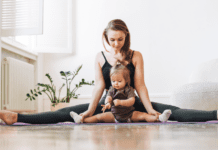 A mom doing yoga holding her toddler.