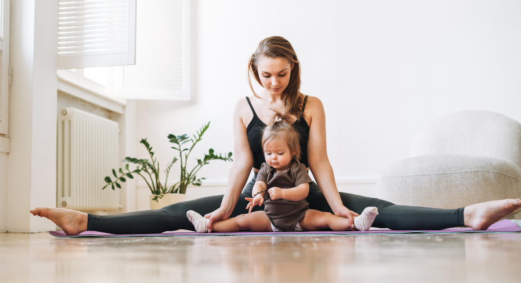 A mom doing yoga holding her toddler.