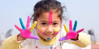 Celebrating Holi A girl with pant on her hands.