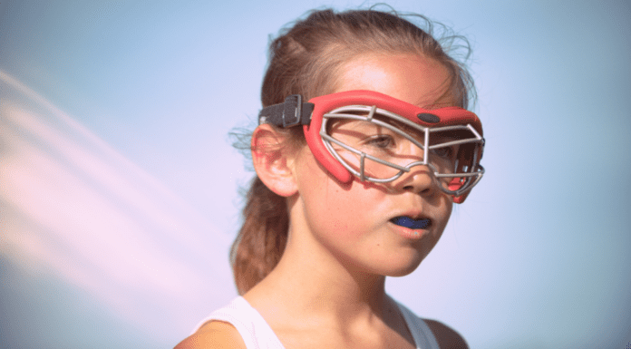 A young girl lacrosse player wearing googles.