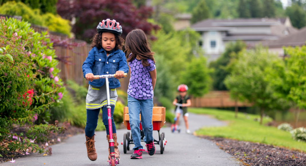 Kids riding their scooters outside during the spring. 