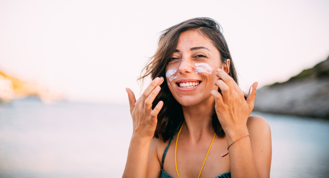 A woman putting sunscreen on her face. 