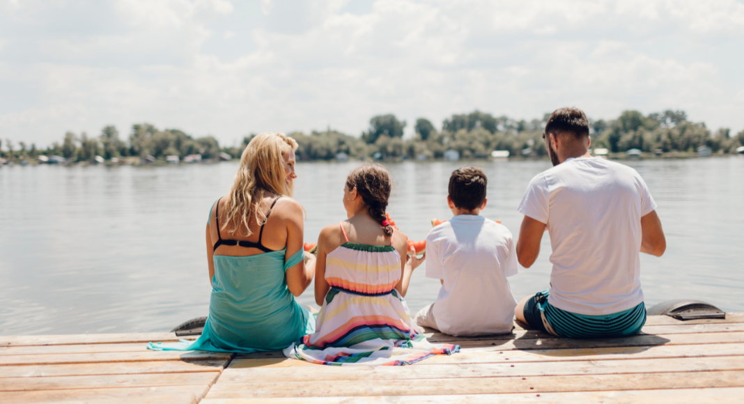 A family sitting on a dock in summer. 