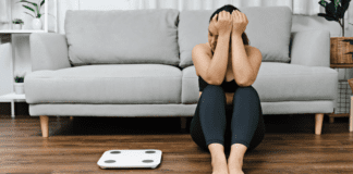 Let’s Stop With The “Buzz Words” A woman sitting and looking sad next to a scale.