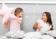 Two girls having a pillow fight at a sleepover.