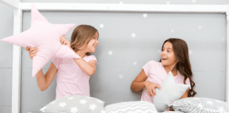 Two girls having a pillow fight at a sleepover.