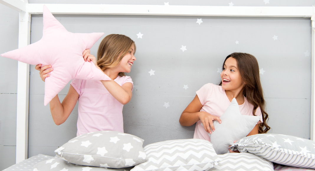 Two girls having a pillow fight at a sleepover. 