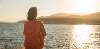 A woman sitting and admiring the view of the ocean.