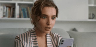 A woman looking surprised on her phone.
