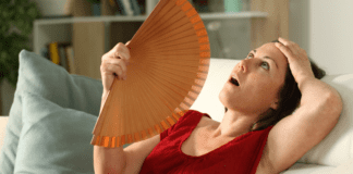 Help, I’m in Perimenopause! A woman fanning herself during a hot flash.