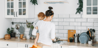 A single mom holding her baby trying to make breakfast.