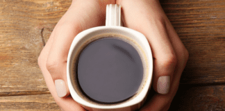 In Honor of National Coffee Day: Coffee & Your Workouts hands holding a cup of coffee.