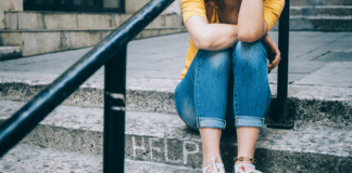 A teen sitting on steps that have the word "help" carved in them.
