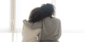 Heard, Hugged, or Helped A mother with her arm around her teen daughter.