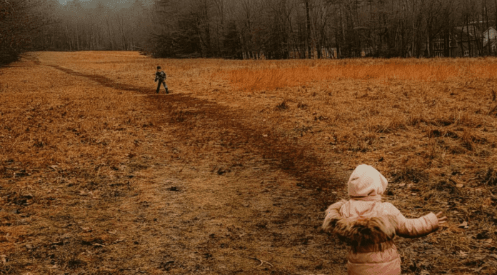 Children hiking on a muddy field.