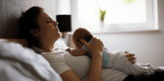 We Need To Talk About Maternal Mental Health A mom postpartum holding her baby in bed.