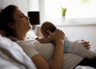 We Need To Talk About Maternal Mental Health A mom postpartum holding her baby in bed.